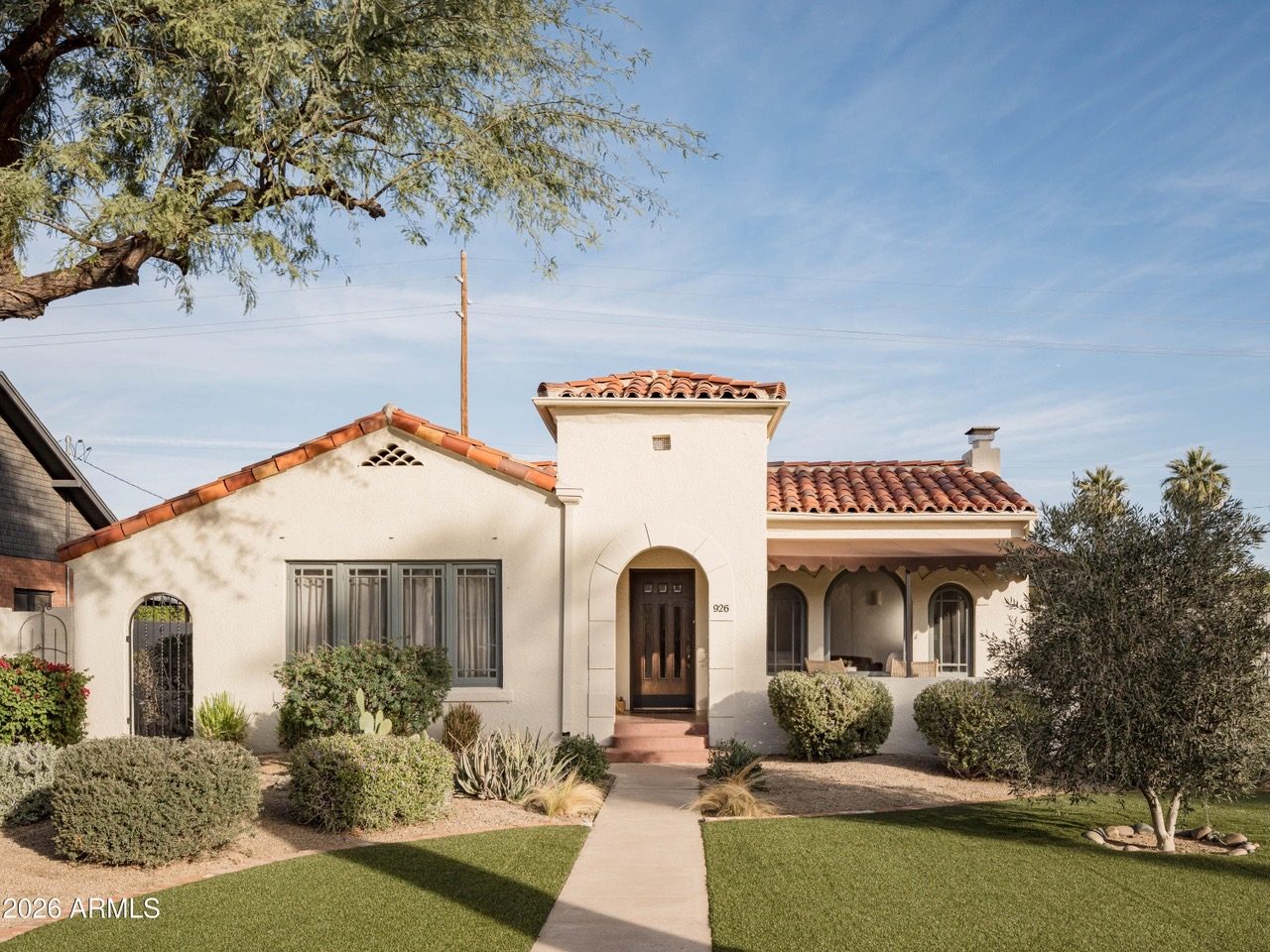 Covered arched porch with rattan chairs and string lights — Arizona Spanish Revival